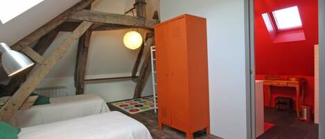 Un dormitorio con dos camas, techo de madera, armario naranja y tragaluz.
