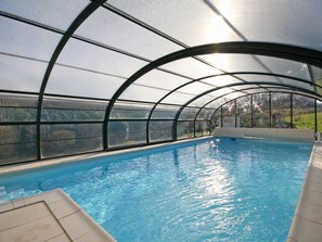 An indoor swimming pool with a curved roof structure, clear glass walls, and a view of the surrounding landscape. - Spacious House with Indoor Pool and Wifi in Laleu (Laleu)
