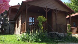 Una casetta di legno con veranda, gradini in pietra e un piccolo giardino.