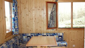 Una baita di legno con un'area salotto con panche, un tavolo e finestre con tende.