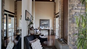 A spacious living area with a stone accent wall, a fireplace, and a comfortable seating arrangement. - A Scenic Canvas, Lakefront - Seasons at Sandpoint (Sandpoint)