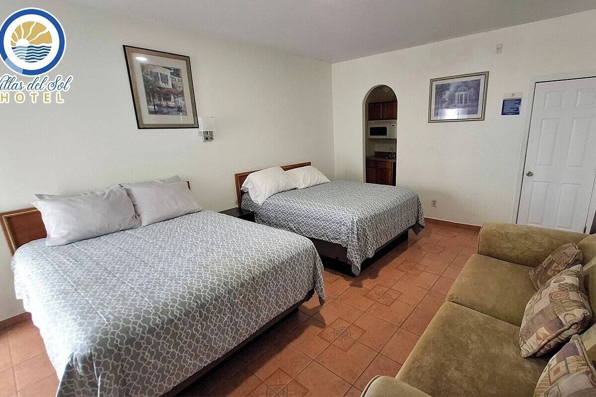Een hotelkamer met twee bedden, een bank, een magnetron en een deur.