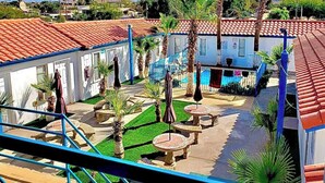 A courtyard with palm trees, outdoor seating, and a swimming pool. - Hotel Villas Del Sol (Golfo de Santa Clara)
