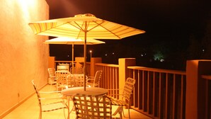 A balcony with outdoor seating, including chairs and tables, and a large umbrella providing shade. - Hotel Villas Del Sol (Golfo de Santa Clara)