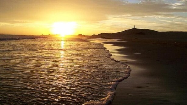 A beach at sunset with the sun low on the horizon, reflecting on the water. - Hotel Villas Del Sol (Golfo de Santa Clara)