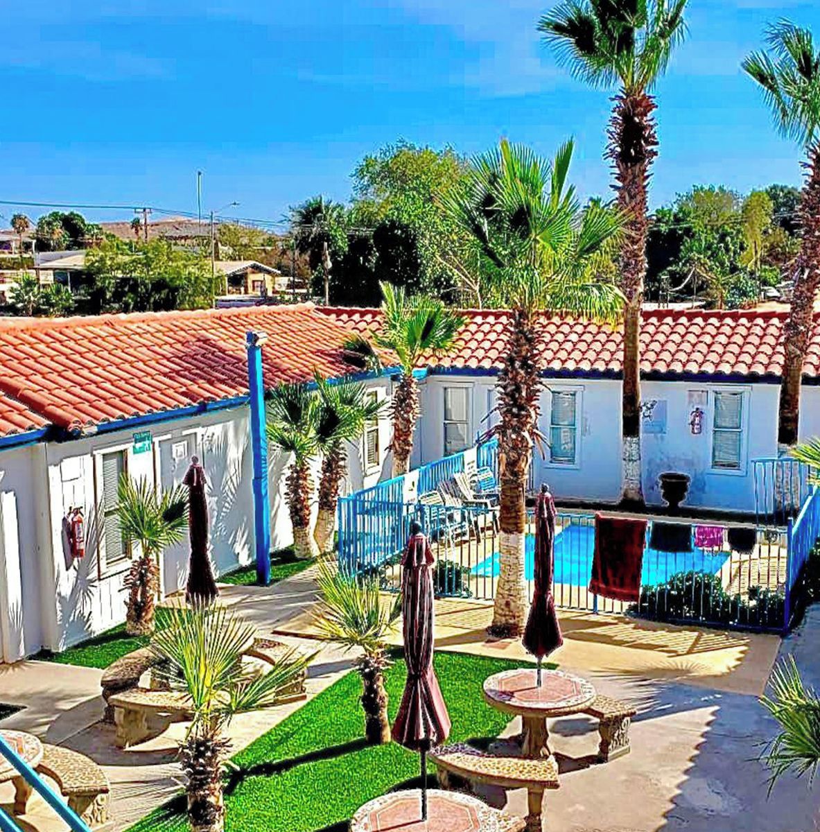 A courtyard with palm trees, outdoor seating, and a pool area at Villas del Sol Hotel.