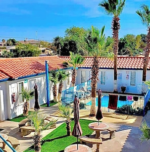 A courtyard with palm trees, outdoor seating, and a pool area at Villas del Sol Hotel.