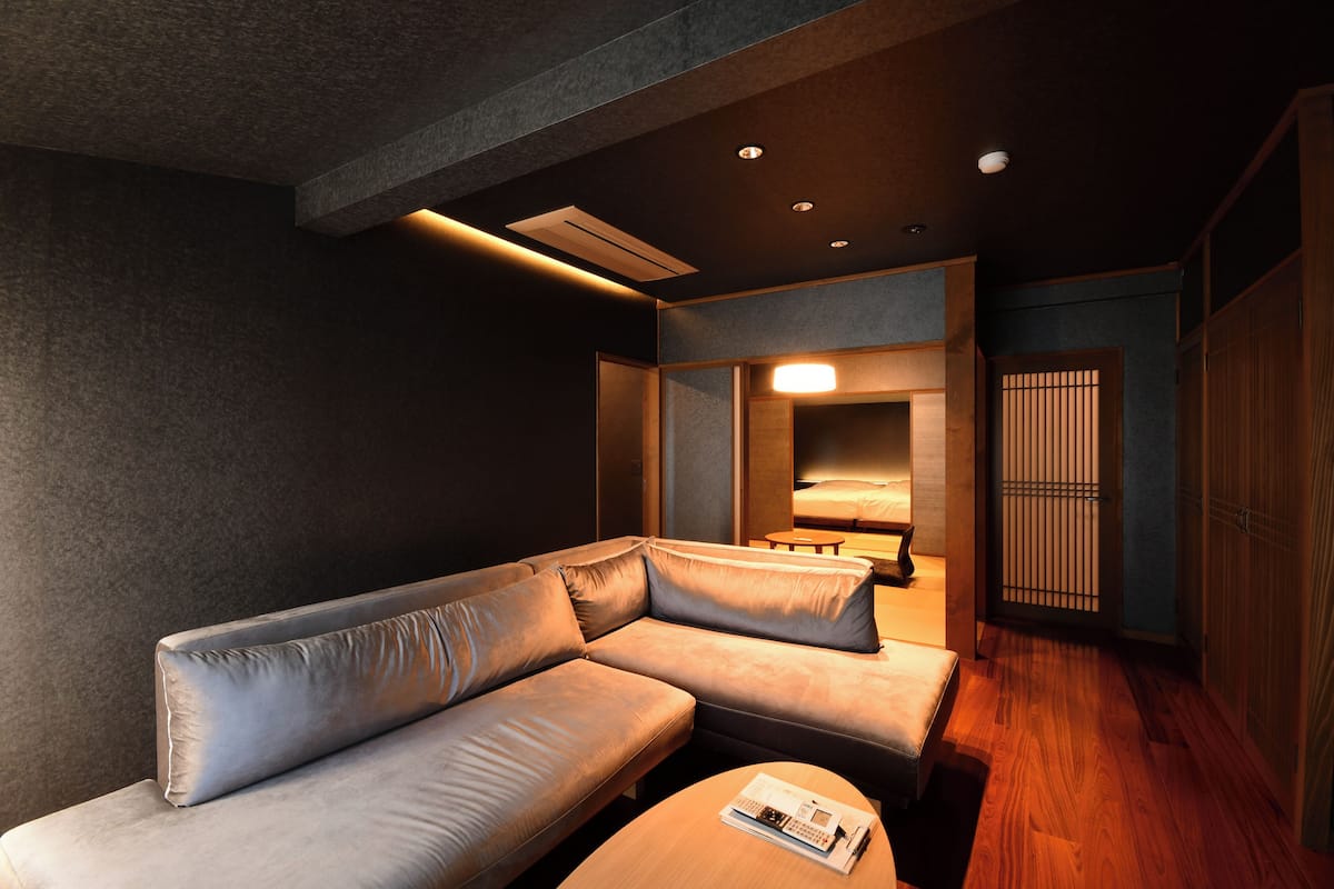 A modern room with a sectional sofa, a small table, and a traditional Japanese sliding door.