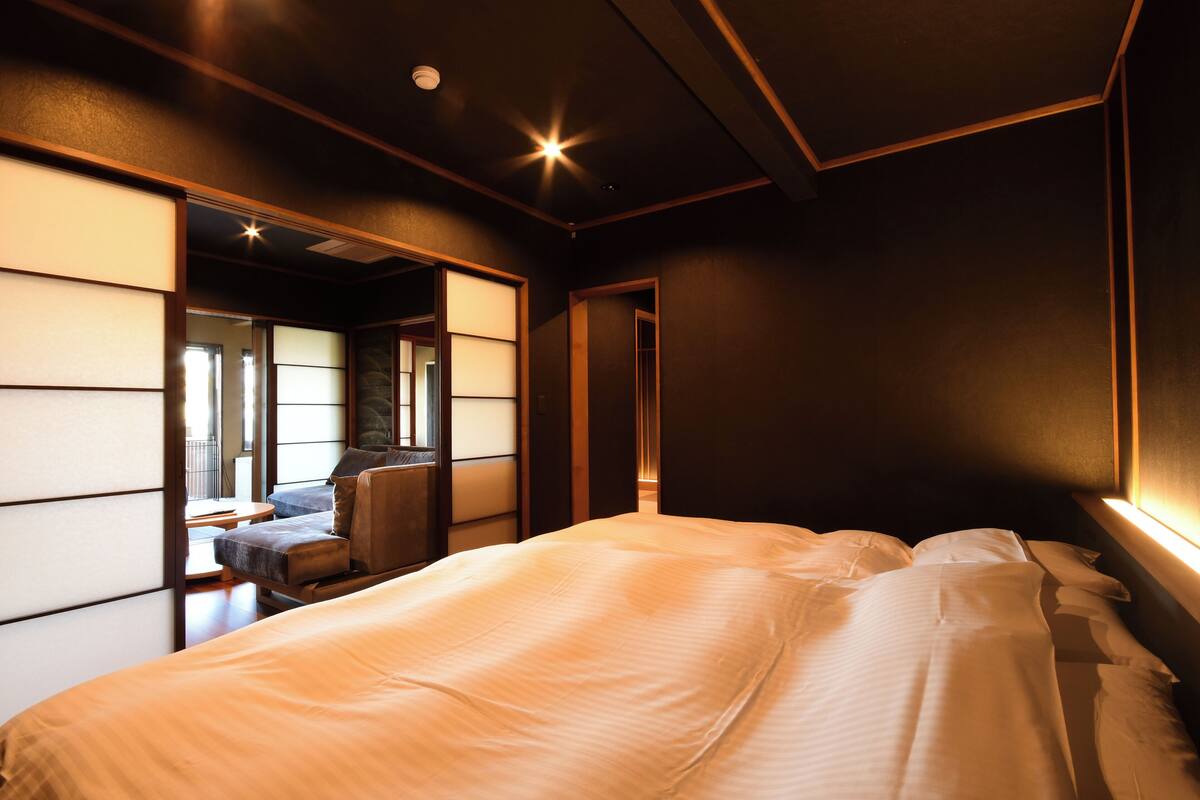 A hotel room with a bed, a seating area, and a view of the outside.