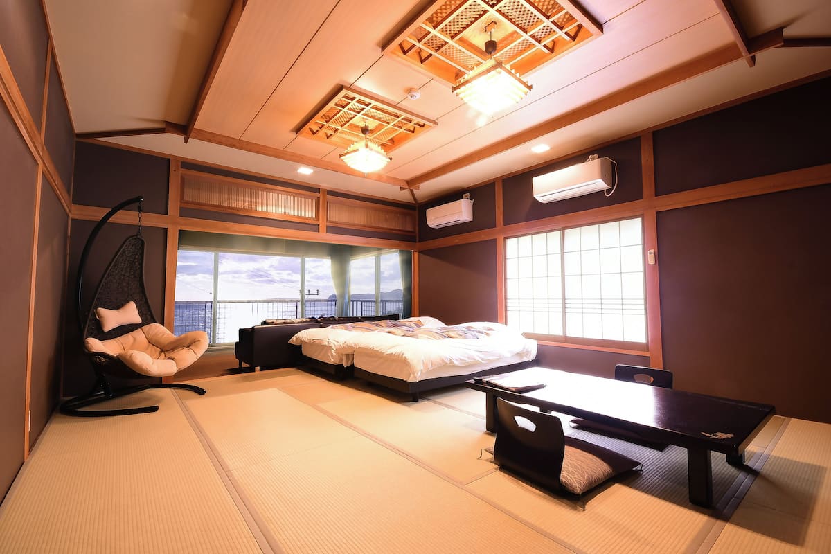 A room with tatami flooring, a bed, a desk, a chair, and a hanging swing.