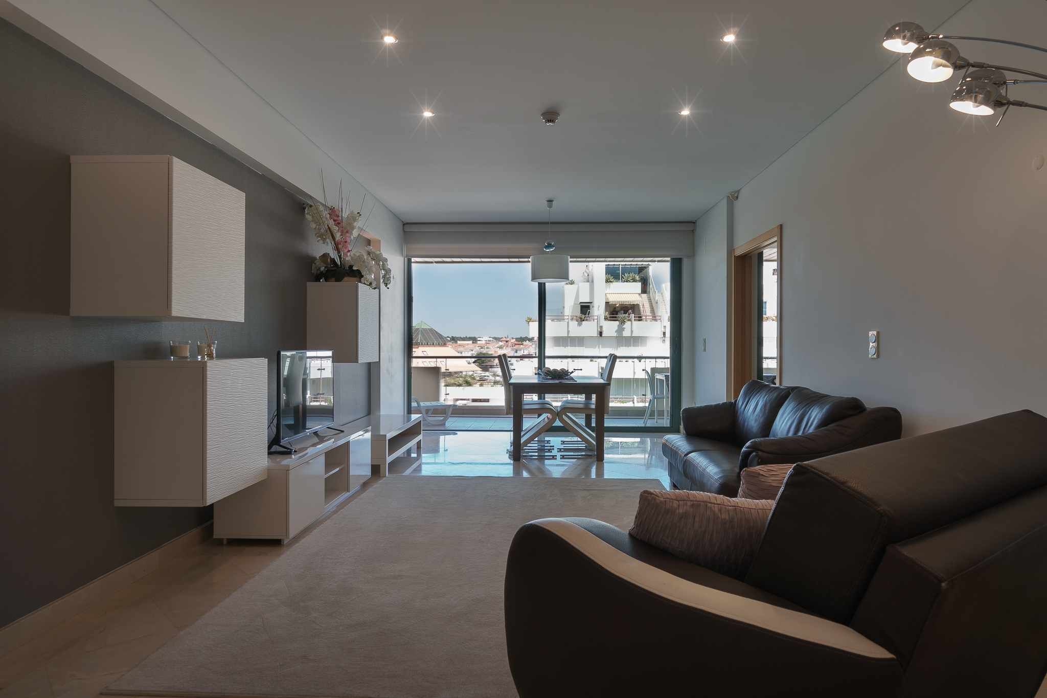 A modern living room with a sofa, TV, and dining area.
