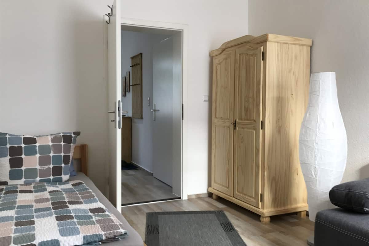 Une chambre à coucher comprenant un lit, une armoire, une porte donnant sur une autre pièce et une petite table.