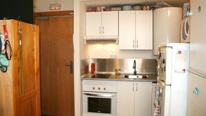 A compact kitchen with white cabinets, a stainless steel sink, a stove, and a refrigerator. - IMPRESSIVE LOFT, MADRID, NEXT TO THE METROPOLITAN WANDA (Madrid)