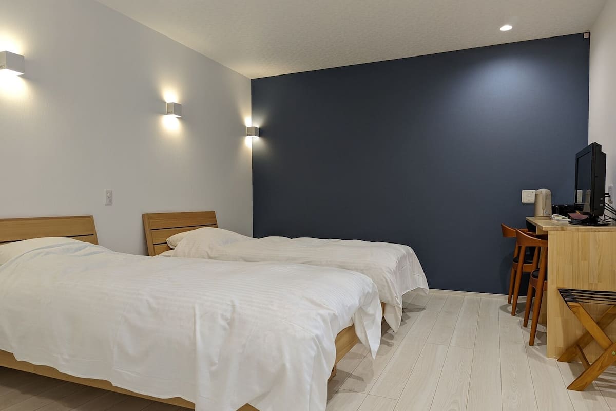 Une chambre avec deux lits, un bureau avec un ordinateur et une chaise.