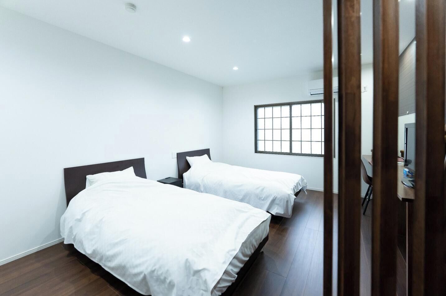 Une chambre d’hôtel avec deux lits, une fenêtre et un bureau avec une chaise.