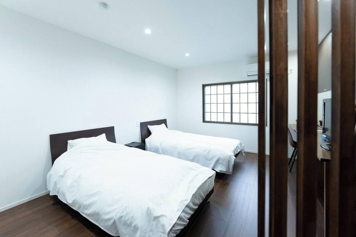 Une chambre d’hôtel avec deux lits, une fenêtre et un bureau avec une chaise.