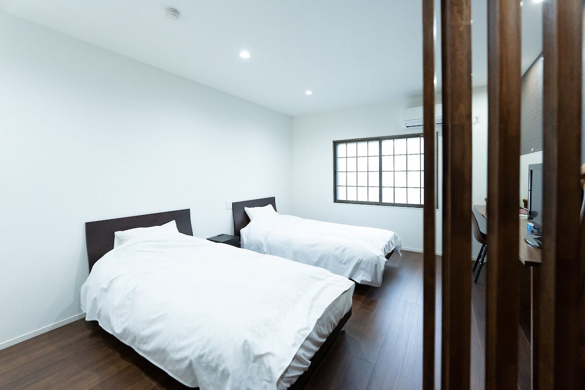 Une chambre avec deux lits, une fenêtre et un bureau avec une chaise.