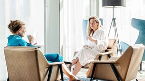 Two people in a well-lit room with large windows, a floor lamp, and modern furniture. - Bergvliet Villa's (Oosterhout)