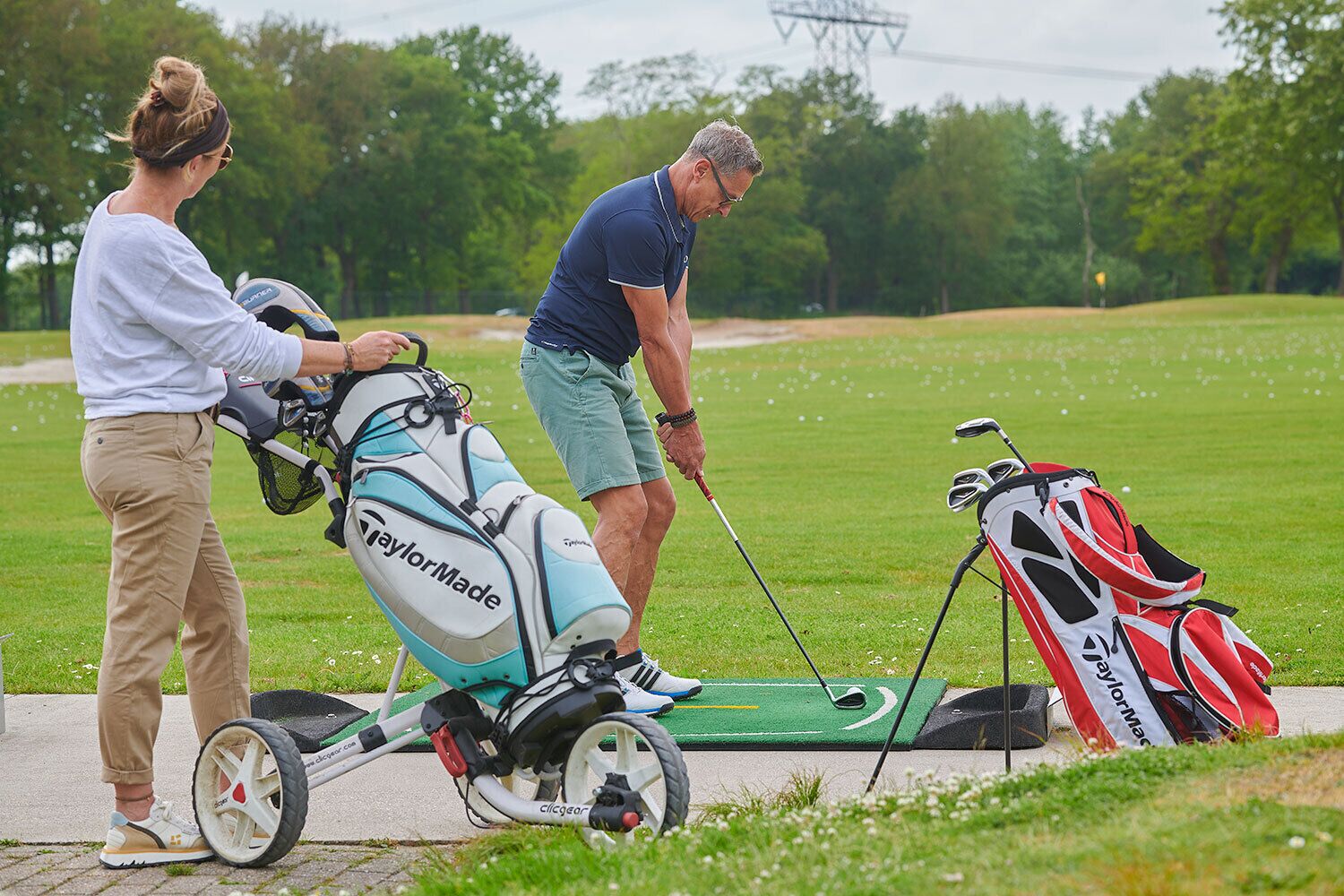 Een golfkarretje met een golfbag en een golfclub op een golfbaan.