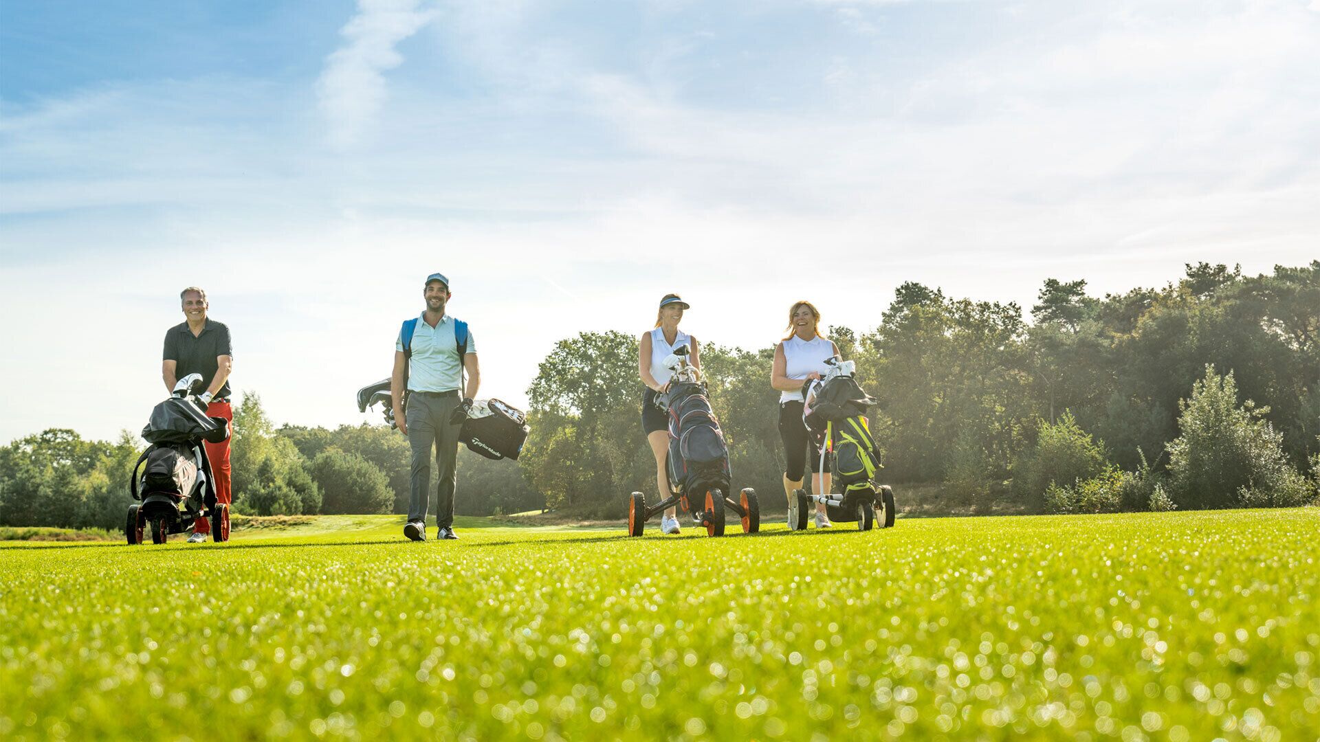 A golf course with people walking and carrying golf bags.