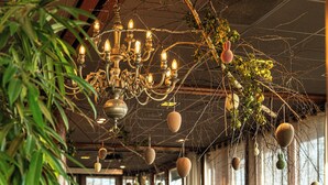 A restaurant with a chandelier, tables, chairs, and large windows. - Bergvliet Villa's (Oosterhout)