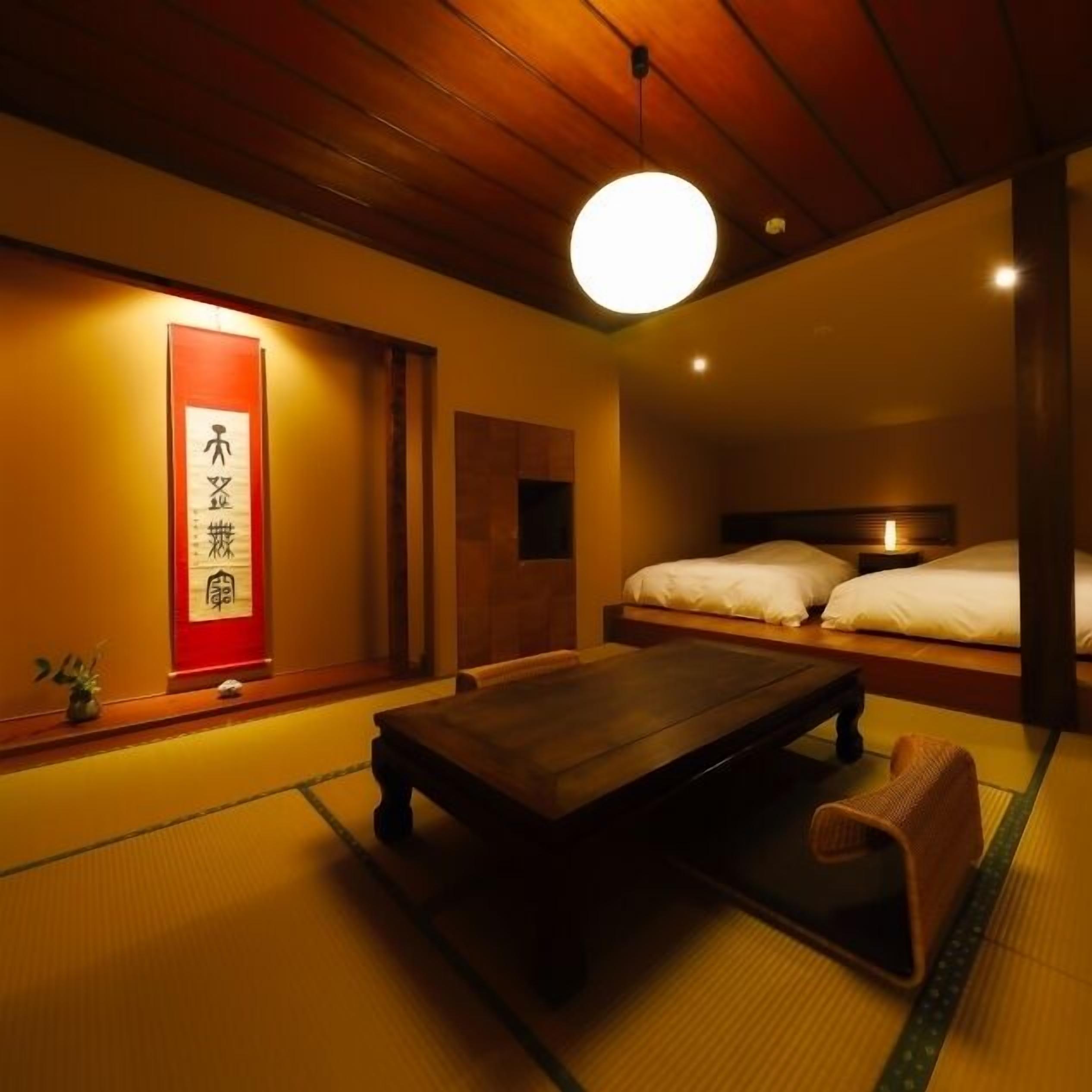 Una habitación japonesa tradicional con suelo de tatami, una mesa de madera baja, una cama con ropa de cama blanca y un letrero rojo con caracteres japoneses.