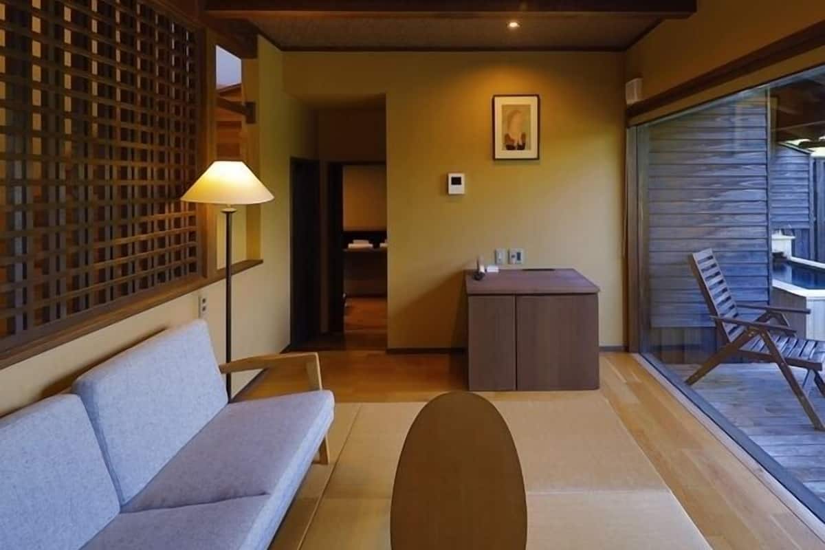 Ein Zimmer mit einer Couch, einer Lampe, einem Schreibtisch und Blick auf einen Pool.