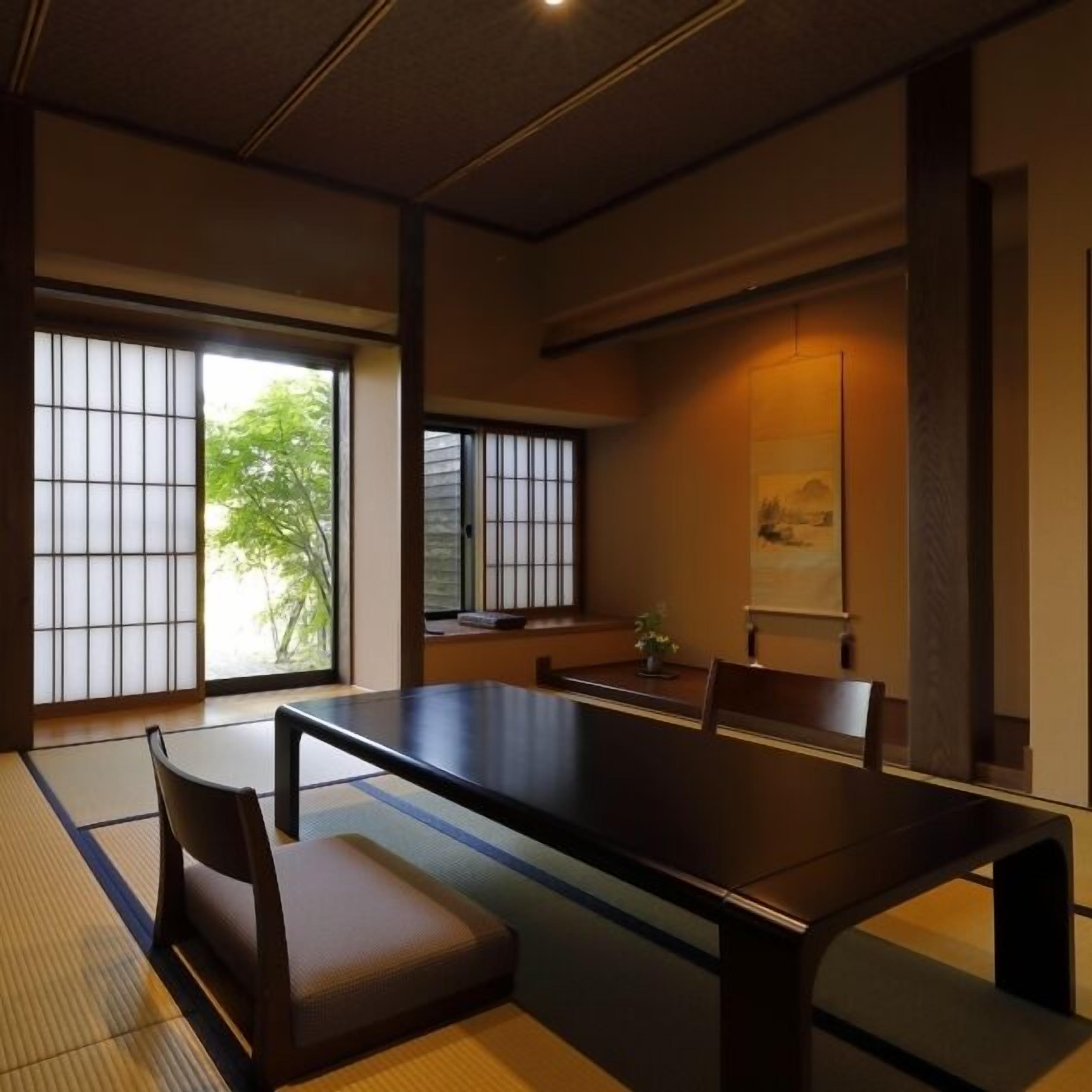 Una habitación japonesa tradicional con suelo de tatami, una mesa baja y puertas correderas.