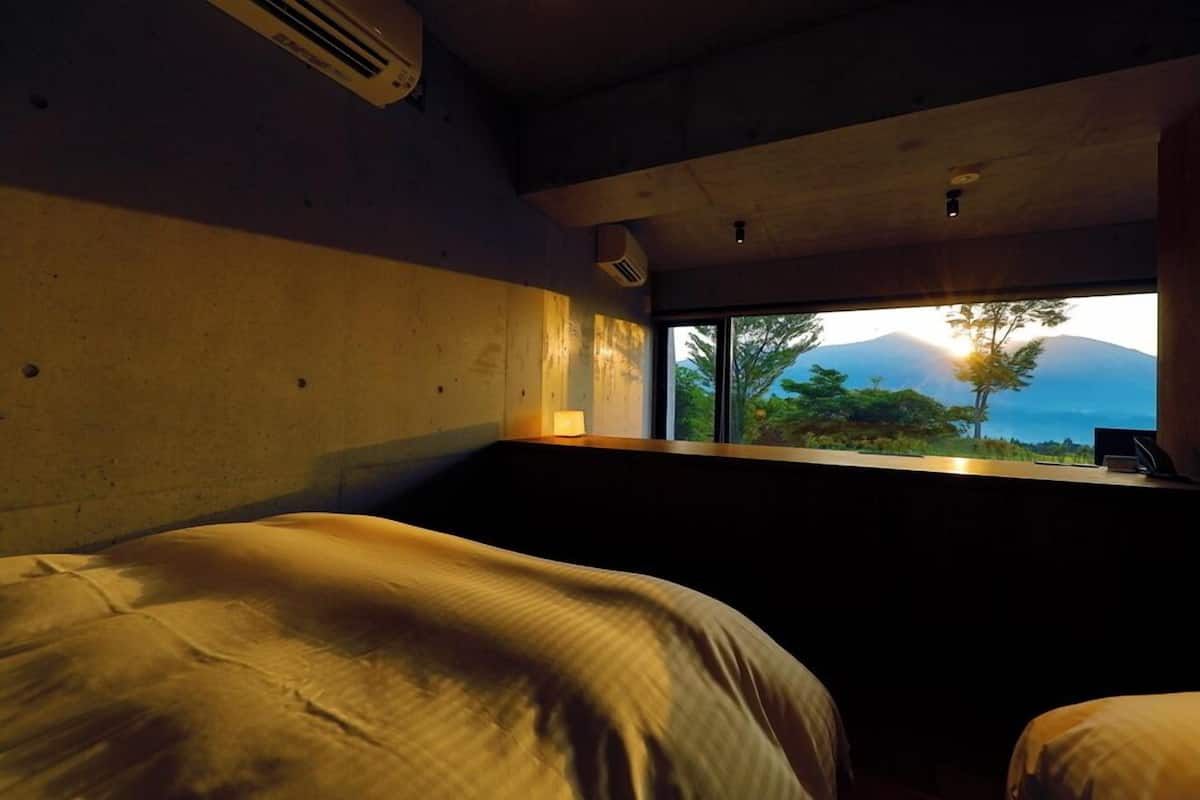 Ein Zimmer mit einem Bett, einem Fenster mit Blick auf die Berge und einem Schreibtisch mit einem Laptop.