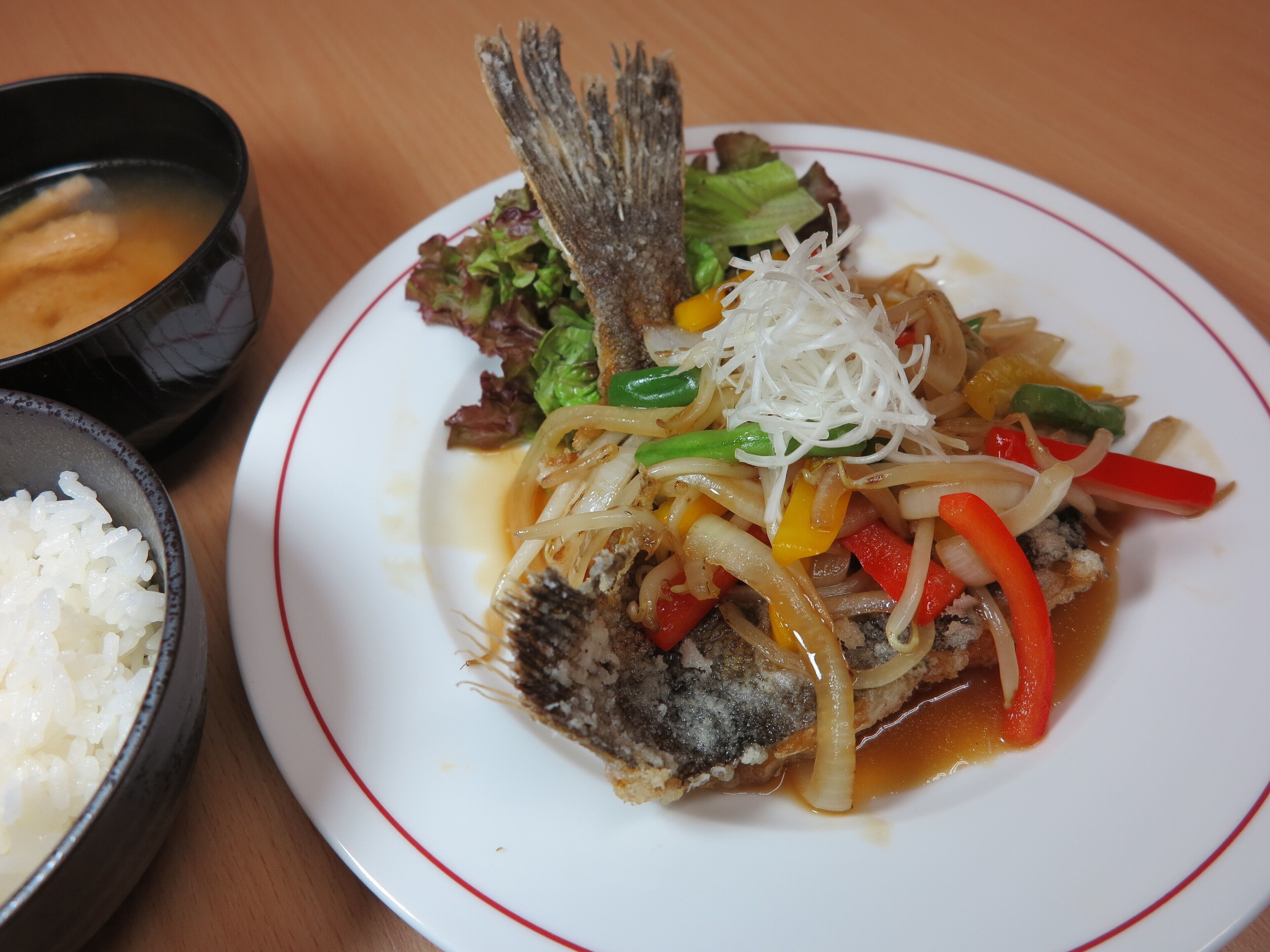 Ein Teller Fisch mit Gemüse und Reis, eine Schüssel Suppe und eine Schüssel Reis.