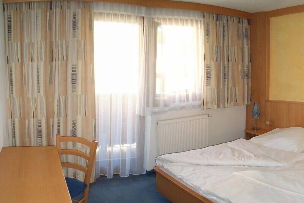 Hotellihuone, jossa on sänky, työpöytä ja tuoli.