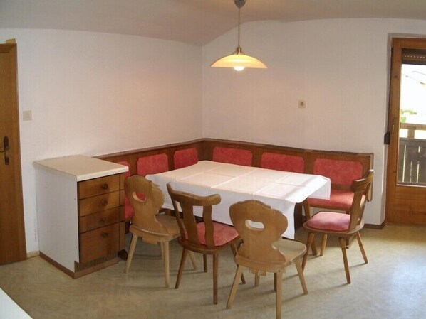 A dining area with a table and chairs, a wooden cabinet, and a hanging light fixture. - Appartements Hirner (Fuegen)