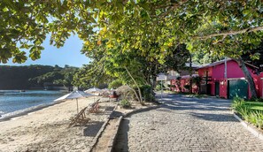 A cobblestone path leading to a beach with umbrellas and lounge chairs. - Villa La Plage (Búzios)