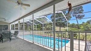 Ein überdachter Außenbereich mit Pool, Stühlen und Deckenventilator.