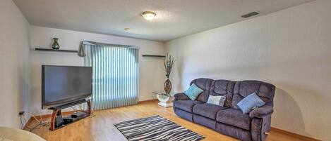 Una sala de estar moderna con un televisor de pantalla plana, un sofá gris, un tapete a rayas y piso de madera.