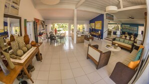 A spacious living area with a high ceiling, a sofa set, a dining table with chairs, and various decorative items. -  Villa Manguinhos (Búzios)