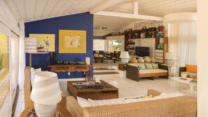 A spacious living area with a blue accent wall, a television, and various decorative items. -  Villa Manguinhos (Búzios)