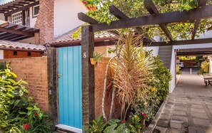 Stunning entrance with a vibrant door, brick wall, and lush garden.