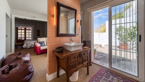 Un baño moderno con un mueble de tocador de madera, un espejo grande y una puerta de vidrio corredera que da a un balcón.