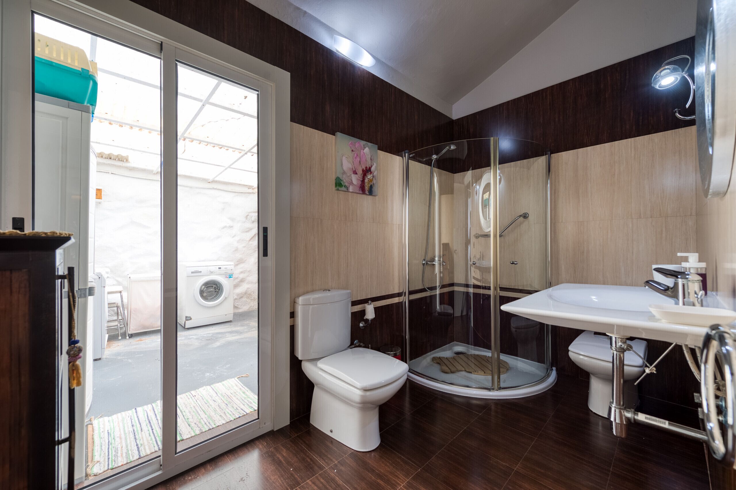 A modern bathroom with a glass-enclosed shower, a white toilet, and a sink with a mirror.