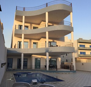 Un immeuble à plusieurs étages doté d’une cour intérieure où se trouve une piscine.