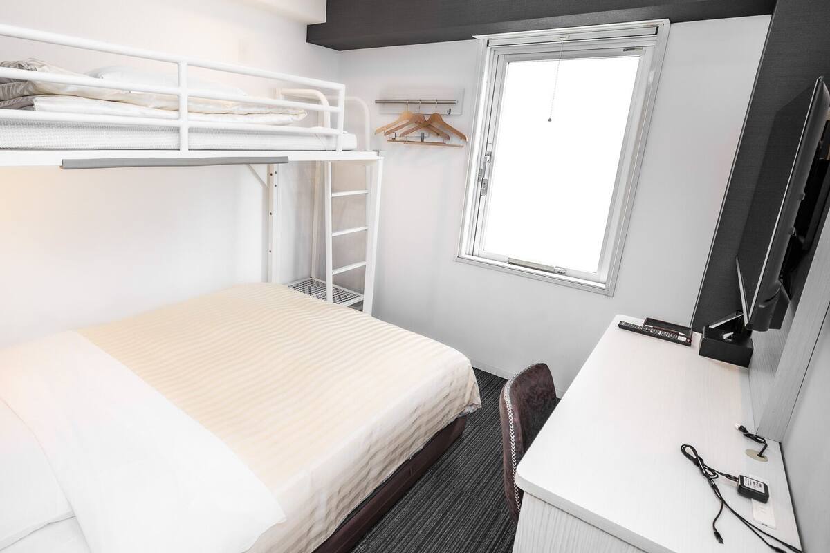 A bunk bed with a desk, a mirror, and a window.