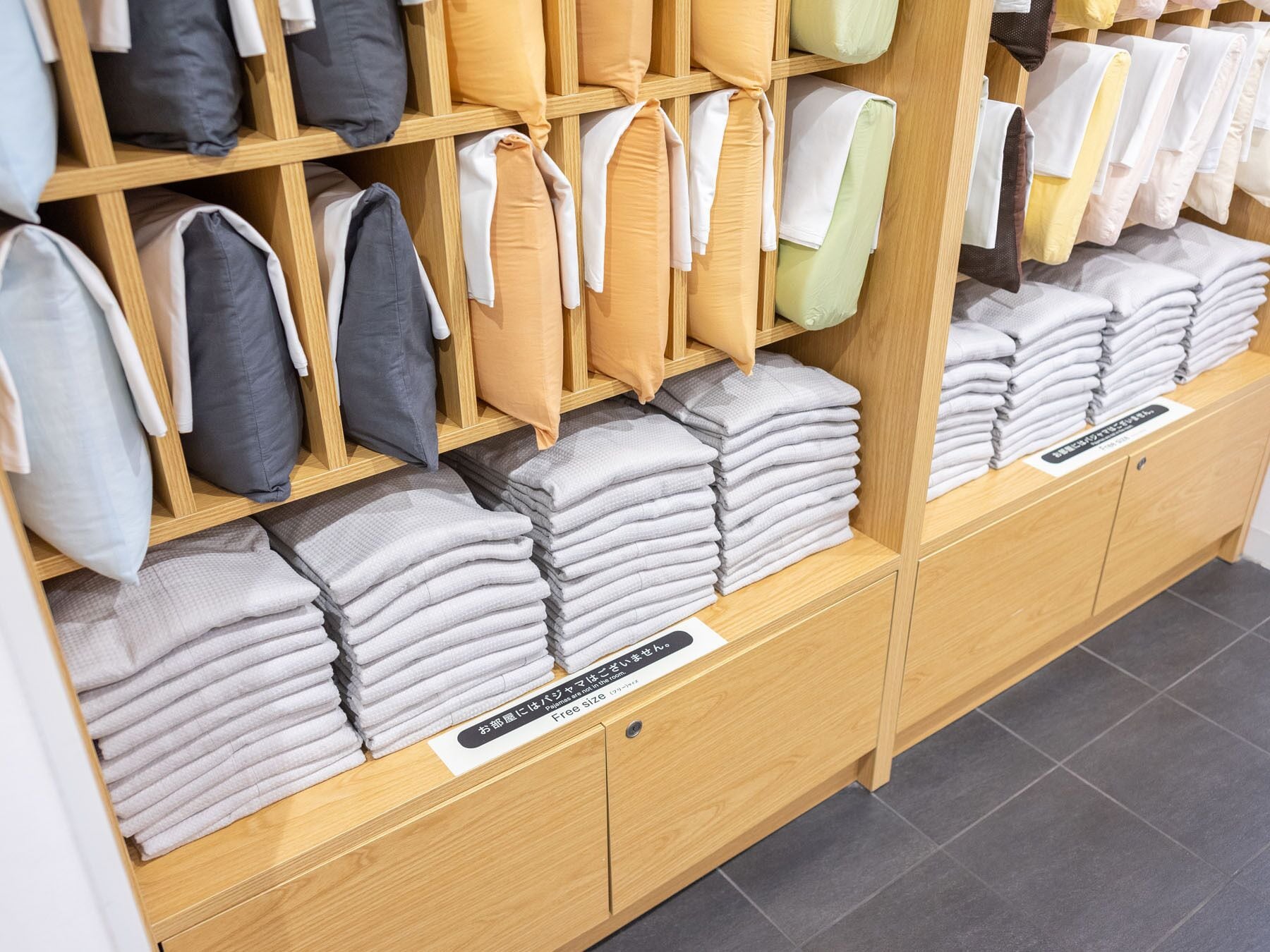 Un magasin où l’on trouve des étagères remplies d’oreillers et de serviettes pliées, disponibles dans différentes couleurs.