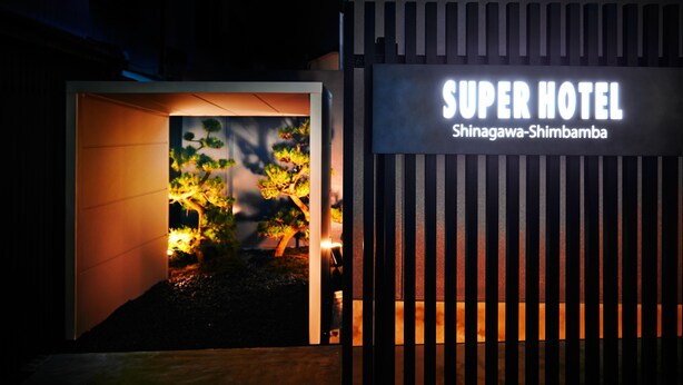L’entrée d’un hôtel, avec une enseigne indiquant : « SUPER HOTEL Shinagawa-Shimbamba ».