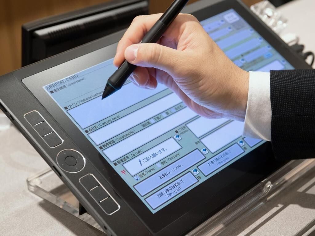 Une personne utilise une tablette pour remplir une carte d’enregistrement à la réception d’un hôtel.