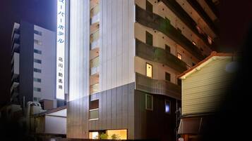 Ein modernes Hotelgebäude mit mehreren Etagen, großen Fenstern und einer auffälligen Beschilderung mit japanischen Schriftzeichen.
