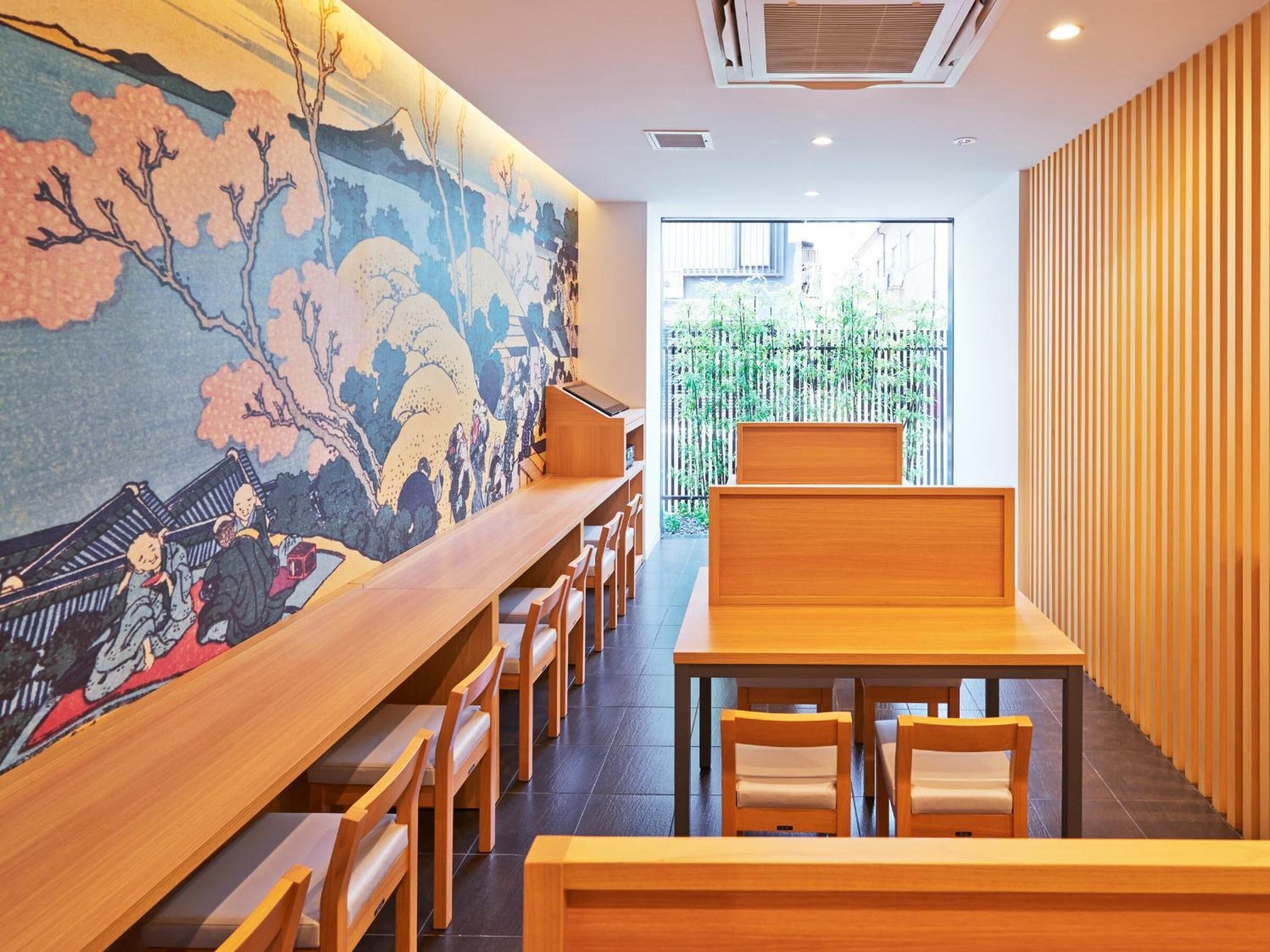 A traditional Japanese restaurant interior with tatami mats, wooden furniture, and a large mural depicting a historical scene.
