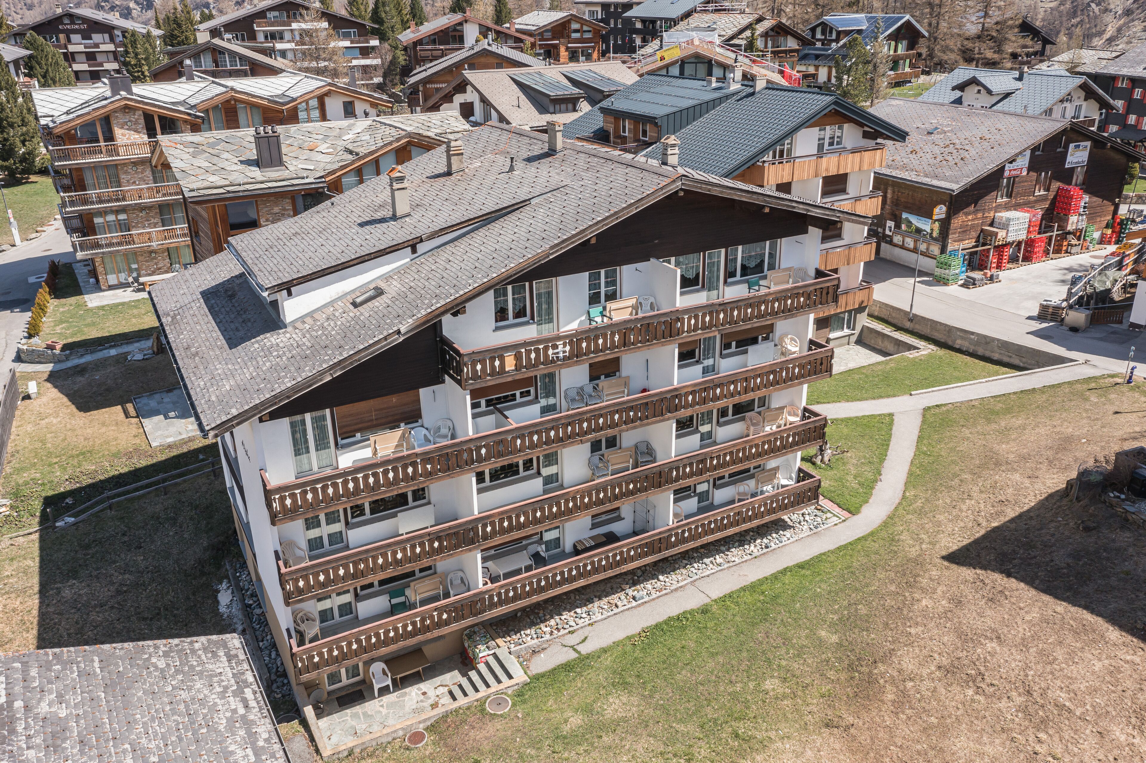 A multi-story hotel with balconies, a ski lift, and a mountain backdrop.