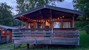 Una cabaña de madera con un porche cubierto, luces colgantes y el número 32 a la vista.