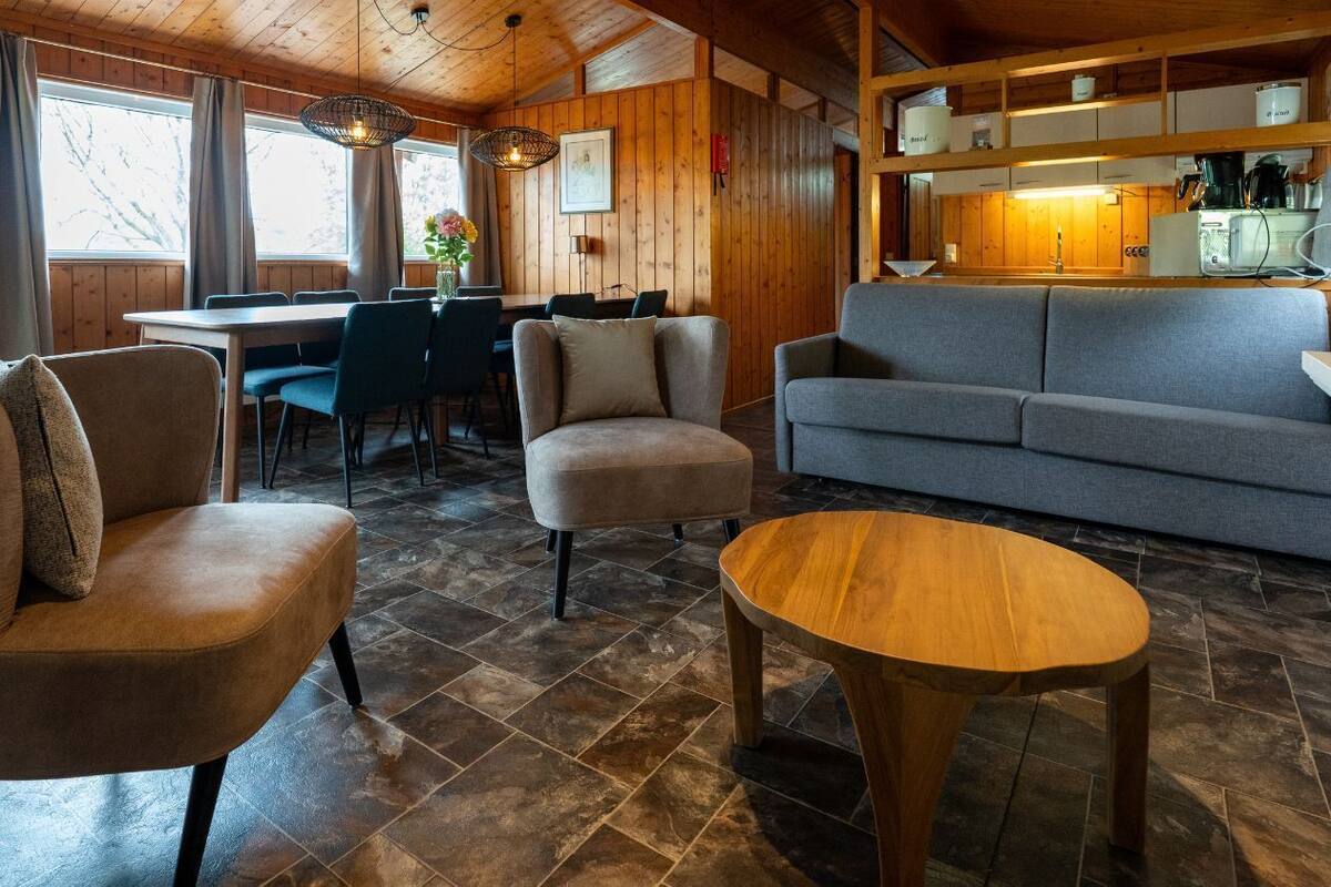 L’intérieur d’un chalet chaleureux, avec un coin repas, un canapé et une table en bois.